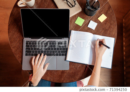 Lady sitting at desk using laptop with blank screen, mockup 71394250
