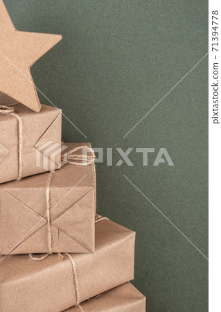 Christmas tree. Boxes in craft paper on green background, closeup. Concept XMAS or New Year holiday. Front view Copy space Christmas tree. Boxes in craft paper on green background, closeup. Concept XMAS or New Year holiday. Front view Copy space 71394778