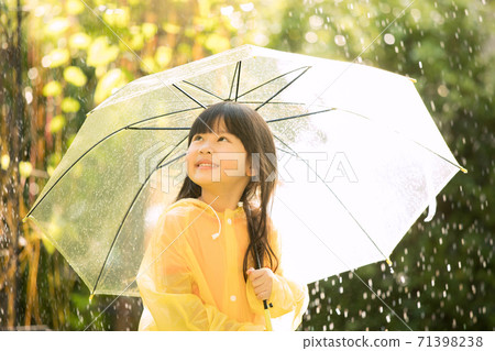 Little girl wearing a raincoat and playing in the rain in the park 71398238