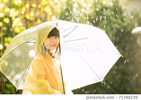 Little girl wearing a raincoat and playing in the rain in the park 71398239