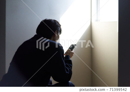 一個人坐著，看著智能手機的後視圖 71399542