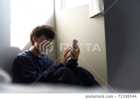 A young man operating a smartphone 71399544
