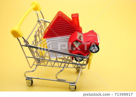 A toy house and a red toy car in a small shopping cart . 71399917