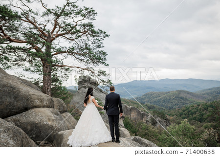 Beautiful gorgeous bride posing to groom and having fun near at mountains with amazing view, space for text, wedding couple Beautiful gorgeous bride posing to groom and having fun near at mountains with amazing view, space for text, wedding couple 71400638