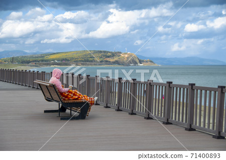Freezing woman, snuggled on deckchair with coffee 71400893