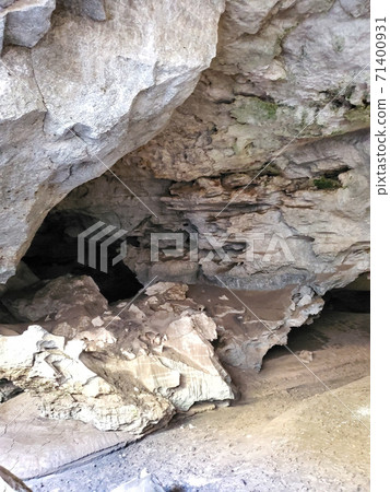 mysterious, unusual cave in a field under the ground. mountain rock walls of the cave, view of the entrance to the deep cave. the reservoir flows directly into the cave. 71400931