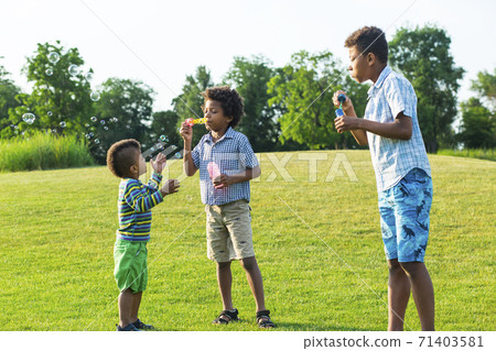Three kids on glade with soap bubble. Three kids on glade with soap bubble. 71403581