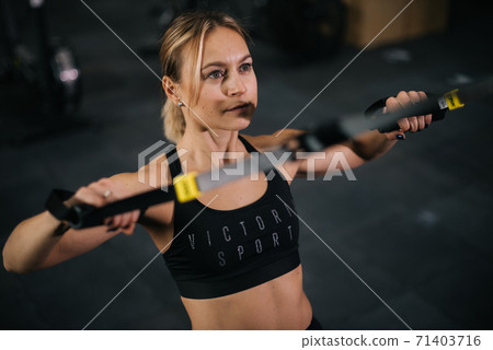 Close-up face of Sportive young woman with perfect muscular body working out on simulator Close-up face of Sportive young woman with perfect muscular body working out on simulator 71403716
