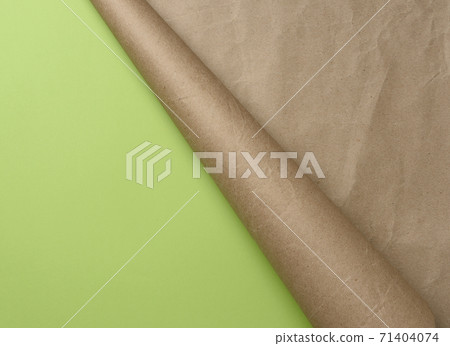 folded corner of a roll of brown paper on a green background folded corner of a roll of brown paper on a green background 71404074