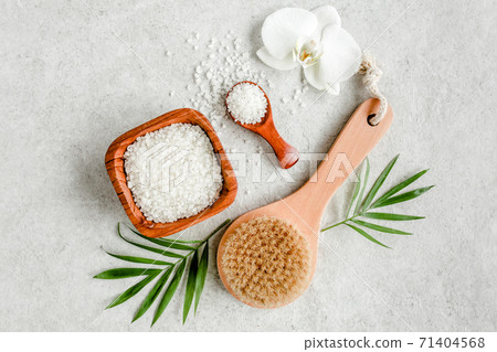 Spa skincare concept. Natural Organic spa cosmetics products, sea salt, massage brush and tropic palm leaves on gray marble table from above.  71404568