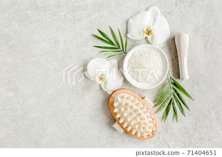 Spa concept. Natural Organic spa cosmetics products, sea salt, massage brush and tropic palm leaves on gray marble table from above. Spa background 71404651