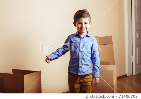 little cute boy in empty room, move to new house. home alone among boxes close up kid smiling, lifestyle real people concept 71406702