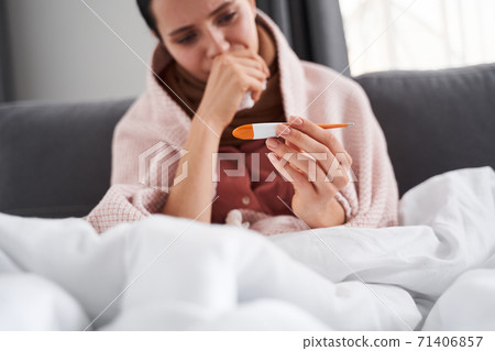 Woman rising thermometer and looking on it Woman rising thermometer and looking on it 71406857