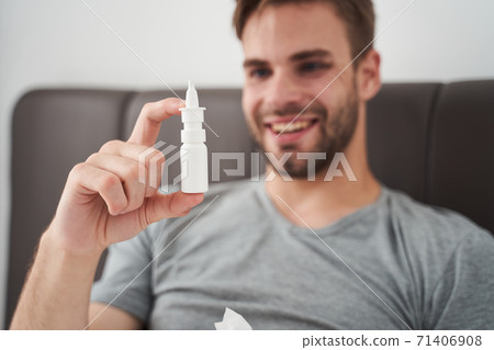 Satisfied man looking joyfully at nasal drops Satisfied man looking joyfully at nasal drops 71406908