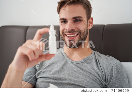 Caucasian man spraying medication into nose Caucasian man spraying medication into nose 71406909