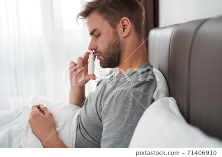 Man using nasal spray to help himself Man using nasal spray to help himself 71406910