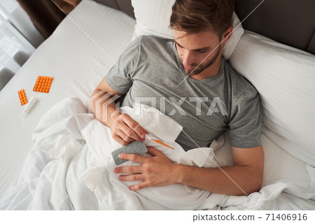 Man looking at temperature on thermometer Man looking at temperature on thermometer 71406916