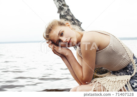 young blond woman hanging on birch tree at lake shore, summer vacations outdoor lifestyle young blond woman hanging on birch tree at lake shore, summer vacations outdoor lifestyle 71407128