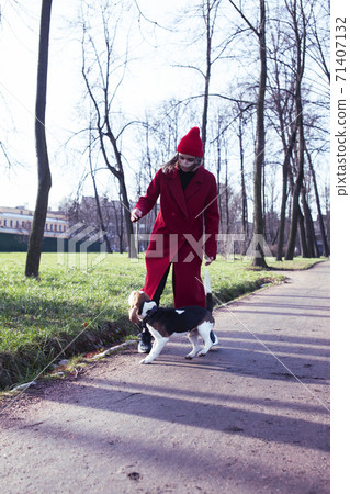 pretty young girl in redd coat playing with dog outside in green park, lifestyle people concept pretty young girl in redd coat playing with dog outside in green park, lifestyle people concept 71407132