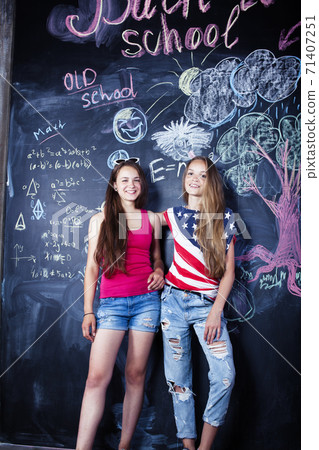 back to school after summer vacations, two teen real girls in classroom with blackboard painted together, lifestyle people concept back to school after summer vacations, two teen real girls in classroom with blackboard painted together, lifestyle people concept 71407251