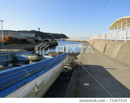 Scenery with a boat near the entrance of the breakwater leading to the lighthouse of the fishing port Scenery with a boat near the entrance of the breakwater leading to the lighthouse of the fishing port 71407524