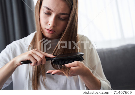 Woman looking at damaged hair tips Woman looking at damaged hair tips 71407669