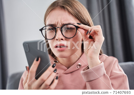 Woman wearing glasses squinting her eyes Woman wearing glasses squinting her eyes 71407693