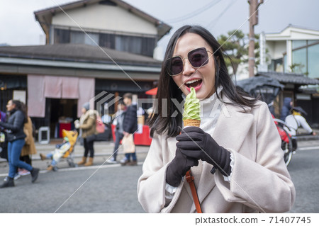 Young tourist woman eating ice cream cone street food at bamboo forest Arashiyama in Japan 71407745