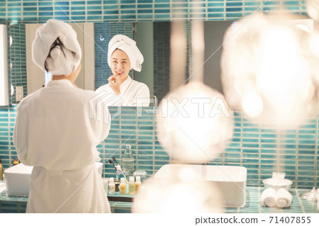 Young woman putting on makeup after shower 71407855