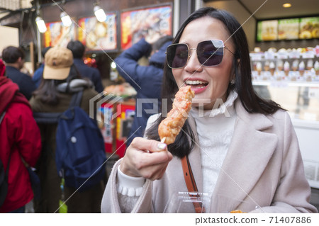 woman eating yakitori, chicken grilled the famous street food at bamboo forest Arashiyama in Japan 71407886
