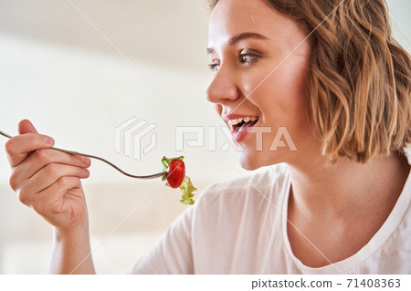 Woman stretching a fork with salad t Woman stretching a fork with salad t 71408363