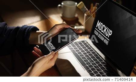 Demale hand using smartphone and laptop on wooden table, include clipping path Demale hand using smartphone and laptop on wooden table, include clipping path 71409414
