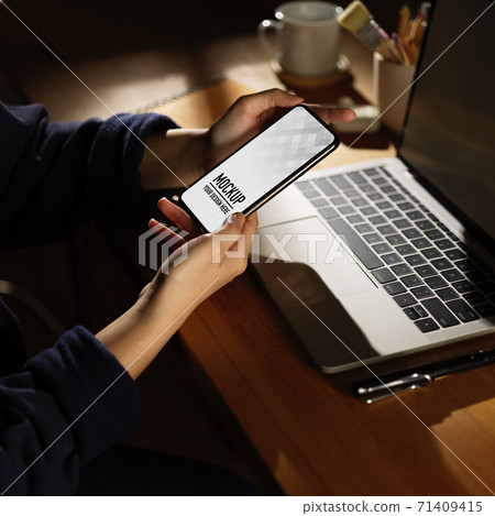Female holding smartphone while working with laptop, clipping path Female holding smartphone while working with laptop, clipping path 71409415