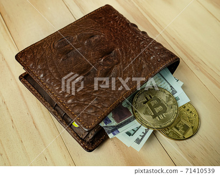 The bitcoin in Crocodile leather wallet  on  wood table. 71410539