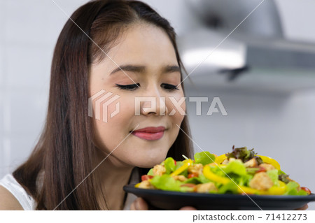 Close up shot of Asian woman smell the dish of salad. Concept woman cooking at home. 71412273