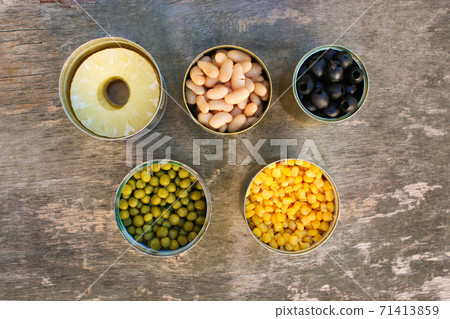 Different open canned food on old wooden background. Top view. Different open canned food on old wooden background. Top view. 71413859
