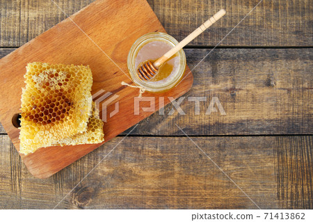 Honey in a jar and honeycomb on an old wooden background. Top view. Honey in a jar and honeycomb on an old wooden background. Top view. 71413862