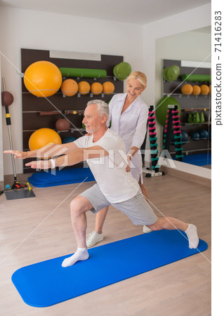 A female physical therapist working with a patient on stretching A female physical therapist working with a patient on stretching 71416283