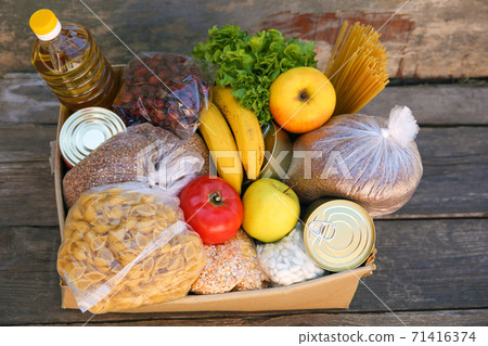 Donation box with food on old wooden background 71416374
