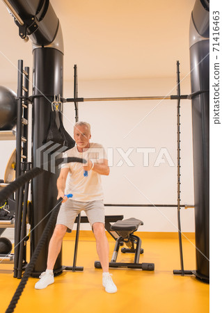A man in sportswear doing exercises in gym and looking concentrated A man in sportswear doing exercises in gym and looking concentrated 71416463