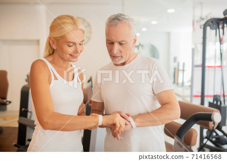 Mature couple checking pulsometers in gym and looking involved 71416568