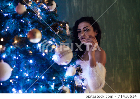 Beautiful woman in dress decorates Christmas tree for new year 71416614