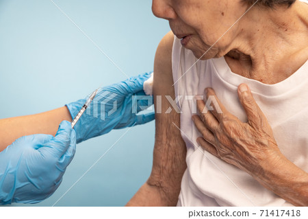 Closeup nurse doing vaccine injection to senior woman. Closeup nurse doing vaccine injection to senior woman. 71417418