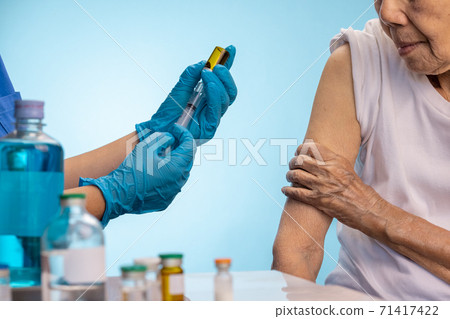 Closeup nurse doing vaccine injection to senior woman. Closeup nurse doing vaccine injection to senior woman. 71417422