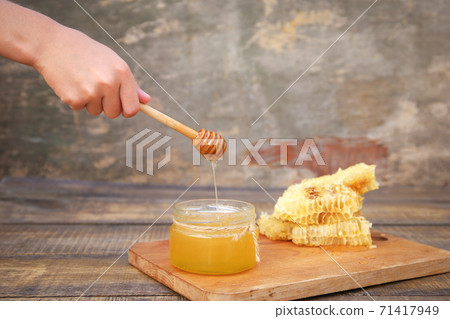 Honey in a jar and honeycomb on an old wooden background. Honey in a jar and honeycomb on an old wooden background. 71417949