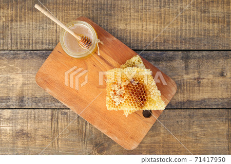 Honey in a jar and honeycomb on an old wooden background. Top view. Honey in a jar and honeycomb on an old wooden background. Top view. 71417950