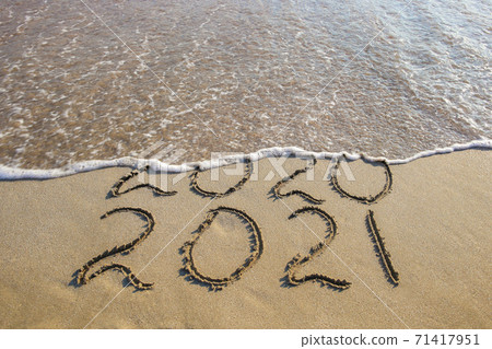 2020, 2021 years written on sandy beach sea. Wave washes away 2020. 2020, 2021 years written on sandy beach sea. Wave washes away 2020. 71417951
