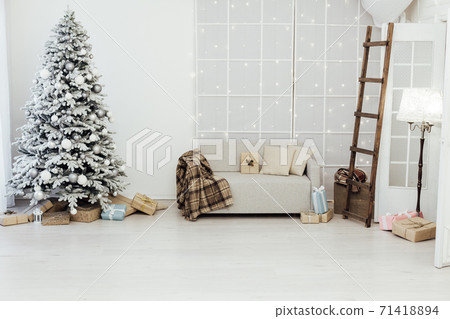 White snowy Christmas tree with gifts decor interior of the house new year postcard 71418894
