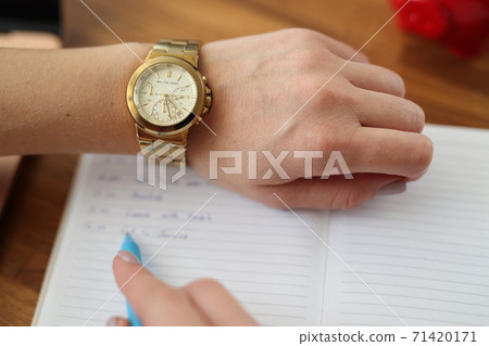 Woman's hand with watch pen next to it lies diary. 71420171