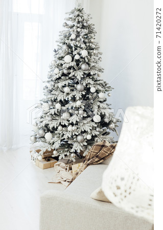 White snowy Christmas tree with gifts decor interior of the house new year postcard 71420272